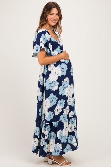 woman wearing a navy blue floral maternity maxi dress with flutter sleeves and a visible baby bump