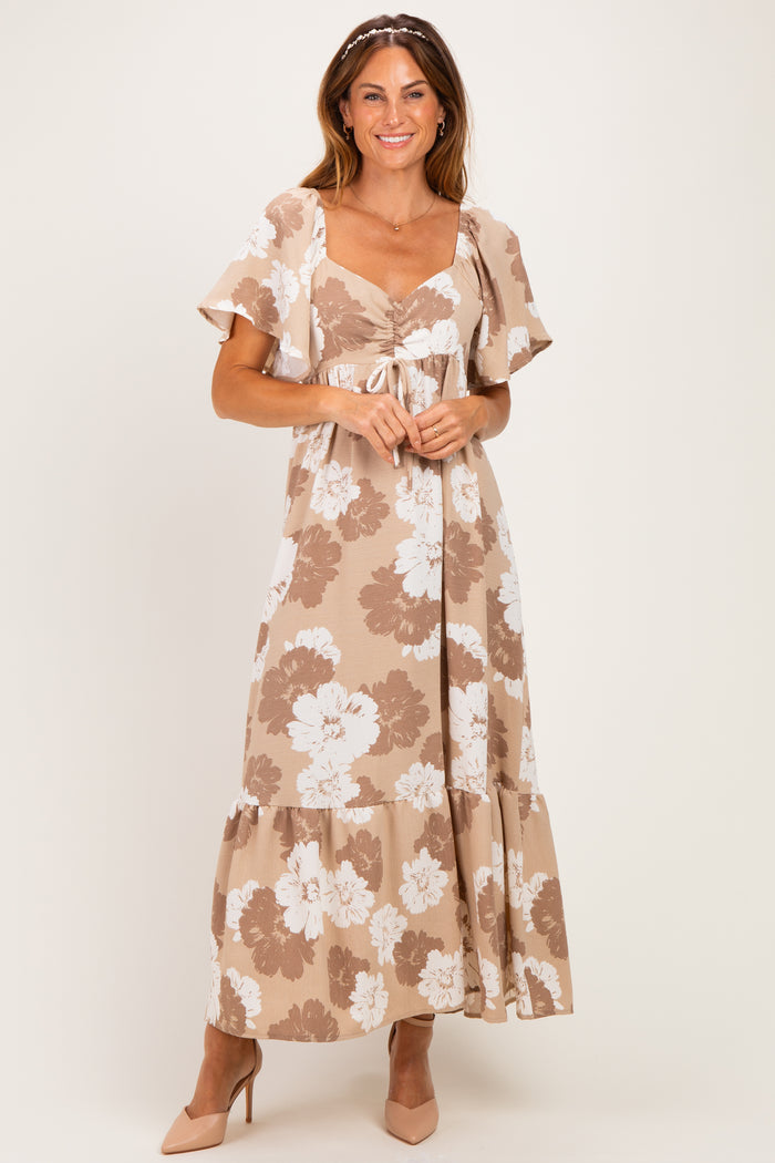 woman wearing a tan floral maxi dress with short flutter sleeves and a tie front detail