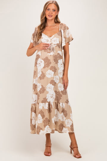 woman wearing a beige floral maternity dress with short flutter sleeves and a baby bump visible