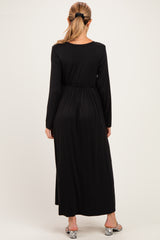woman wearing a black long sleeve maternity dress with a cinched waist and flowy design, showing her pregnant belly from the back