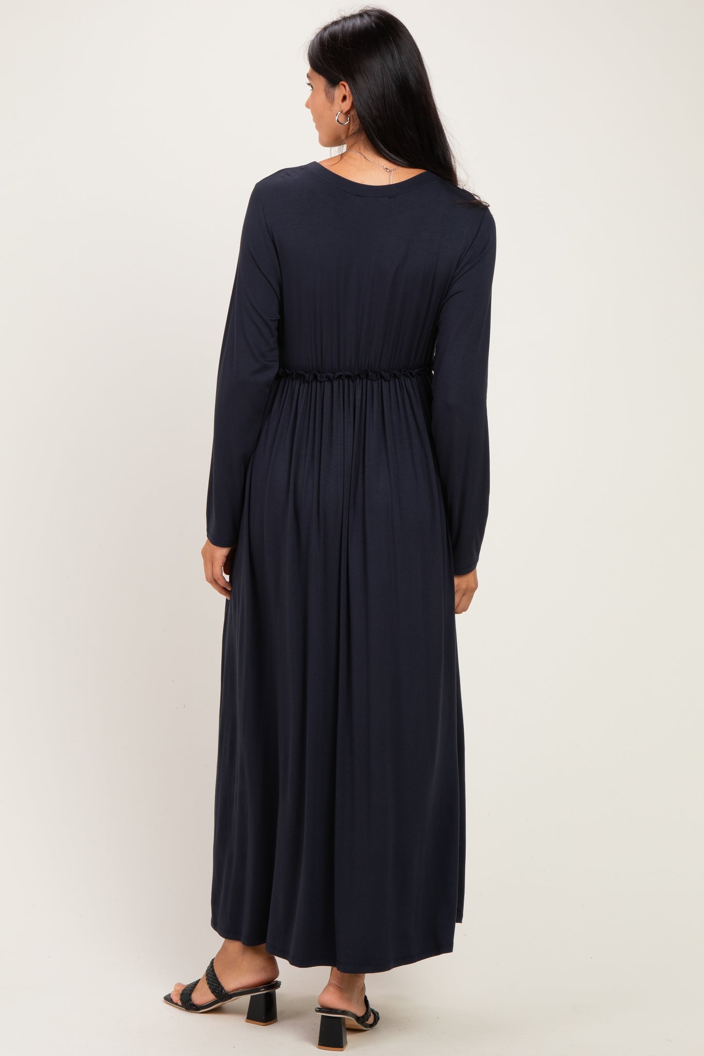 woman wearing a long navy blue dress with a cinched waist and long sleeves