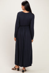 woman wearing a long navy blue dress with a cinched waist and long sleeves