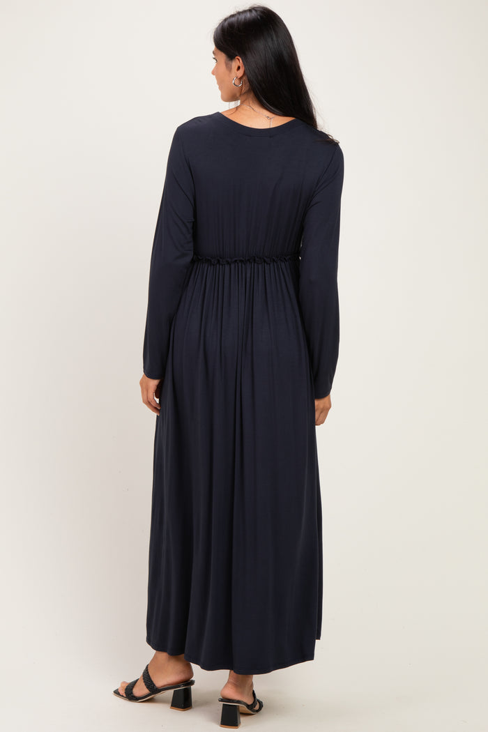 woman wearing a long navy blue dress with a cinched waist and long sleeves