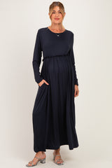 woman wearing a navy long sleeve maternity dress with a waist tie and pockets, and showing her baby bump