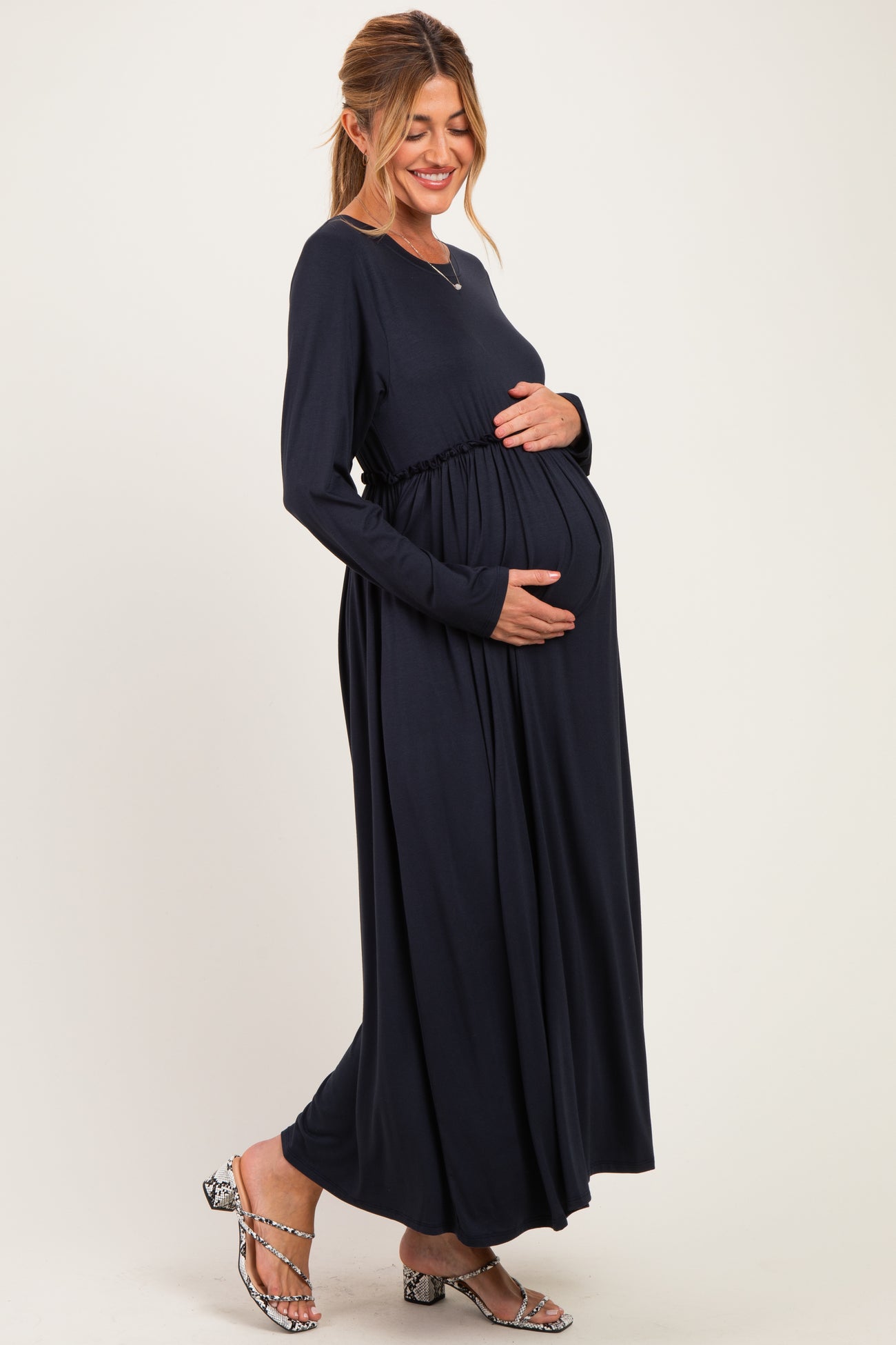 woman wearing a navy blue long sleeve maternity dress and holding her baby bump