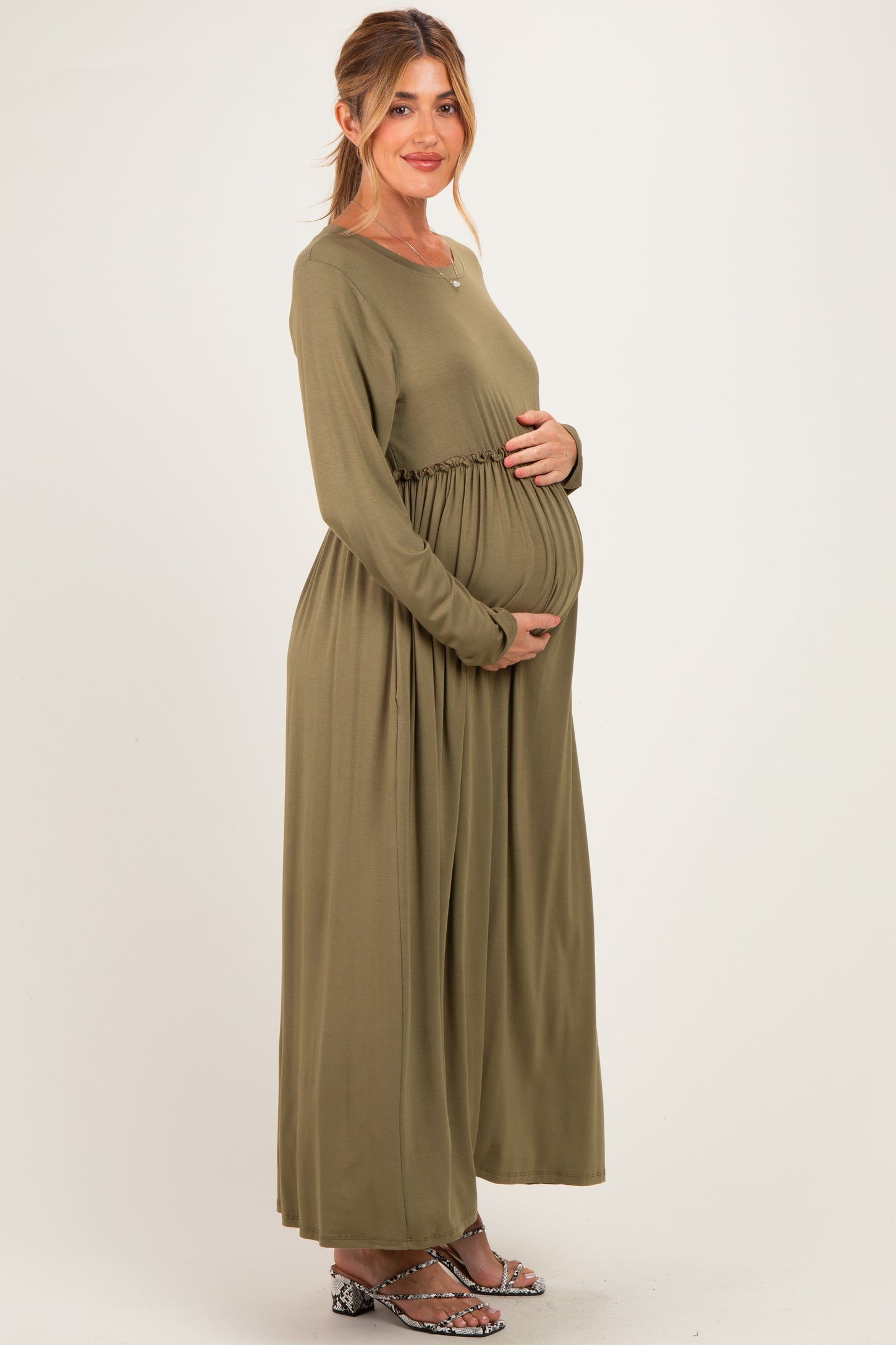 woman wearing an olive green long sleeve maternity dress with an elastic waist and visible baby bump