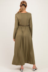 woman wearing an olive green long sleeve maternity maxi dress with an elastic waist from the back