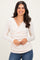 woman wearing a light pink long sleeve wrap top with a fitted silhouette and scoop neckline, smiling at the camera