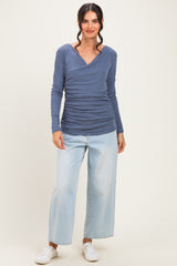 woman wearing a blue long sleeve ruched top with a v-neck and light wash wide-leg jeans
