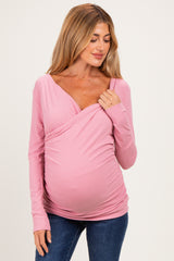 woman wearing a pink long sleeve maternity top with a wrap design and visible baby bump