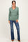 woman wearing a green long sleeve wrap top with vertical ribbing and flared jeans