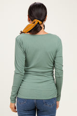 woman wearing a green ribbed long sleeve top with a scoop back and styled hair with a yellow scarf