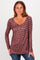 woman wearing a mauve long sleeve henley shirt with floral print and button detail, posing with hands on hips