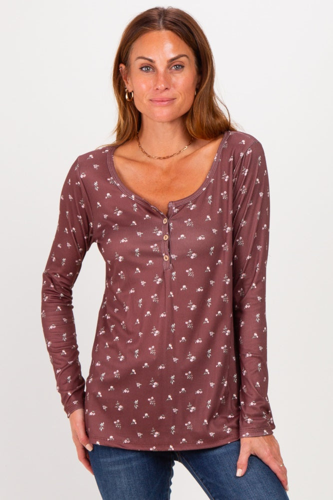 woman wearing a mauve long sleeve henley shirt with floral print and button detail, posing with hands on hips