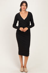 woman wearing a black long sleeve ribbed wrap dress with a fitted silhouette and a v-neckline