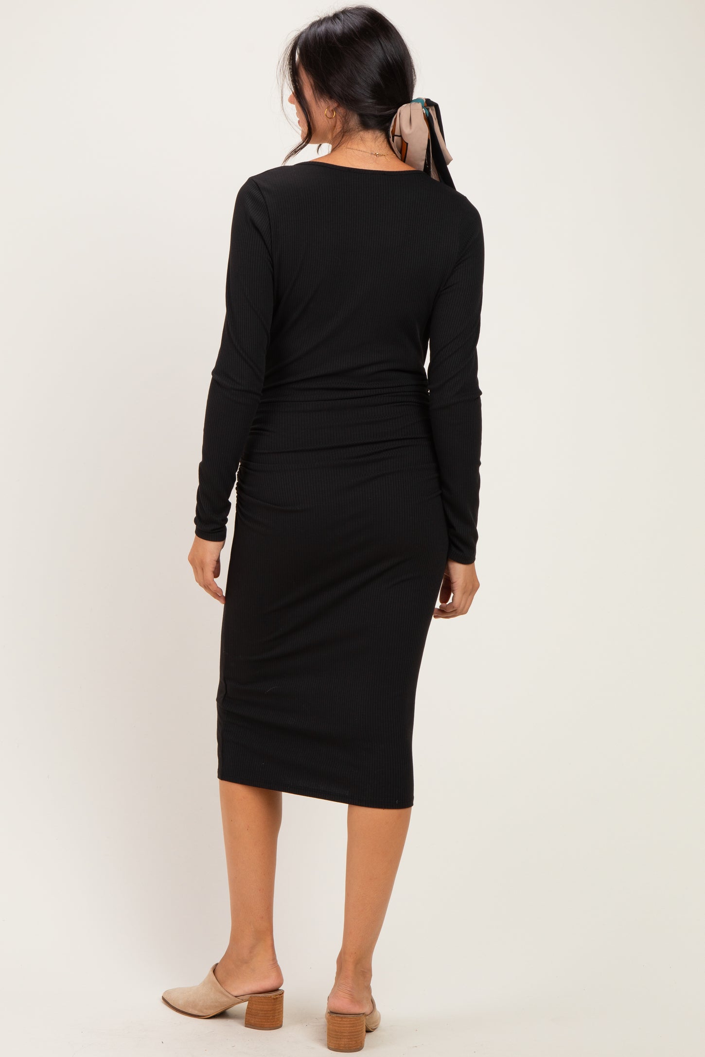 woman wearing a black long sleeve midi dress with a fitted silhouette and back detailing