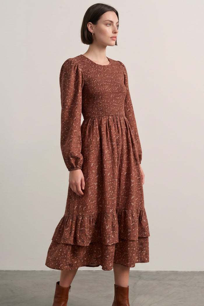 woman wearing a brown floral printed long sleeve dress with ruffle hem and smocked bodice