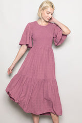 woman wearing a dusty pink short sleeve smocked dress with a tiered skirt and flutter sleeves