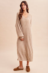 woman wearing a beige ribbed knit maxi sweater dress with long sleeves and a v-neckline, standing against a neutral background