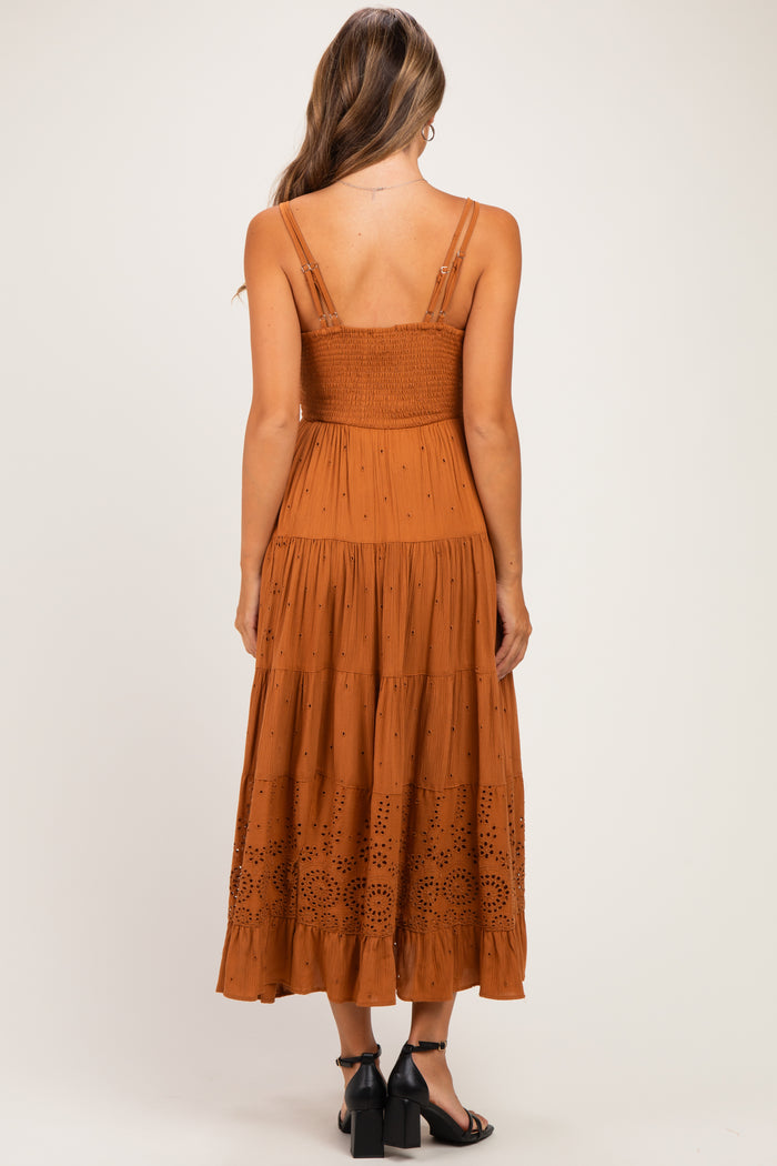 woman wearing a rust brown maternity maxi dress with a smocked bodice and embroidered detailing