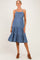 woman wearing a denim blue maternity dress with tiered ruffles and spaghetti straps, standing with a relaxed pose