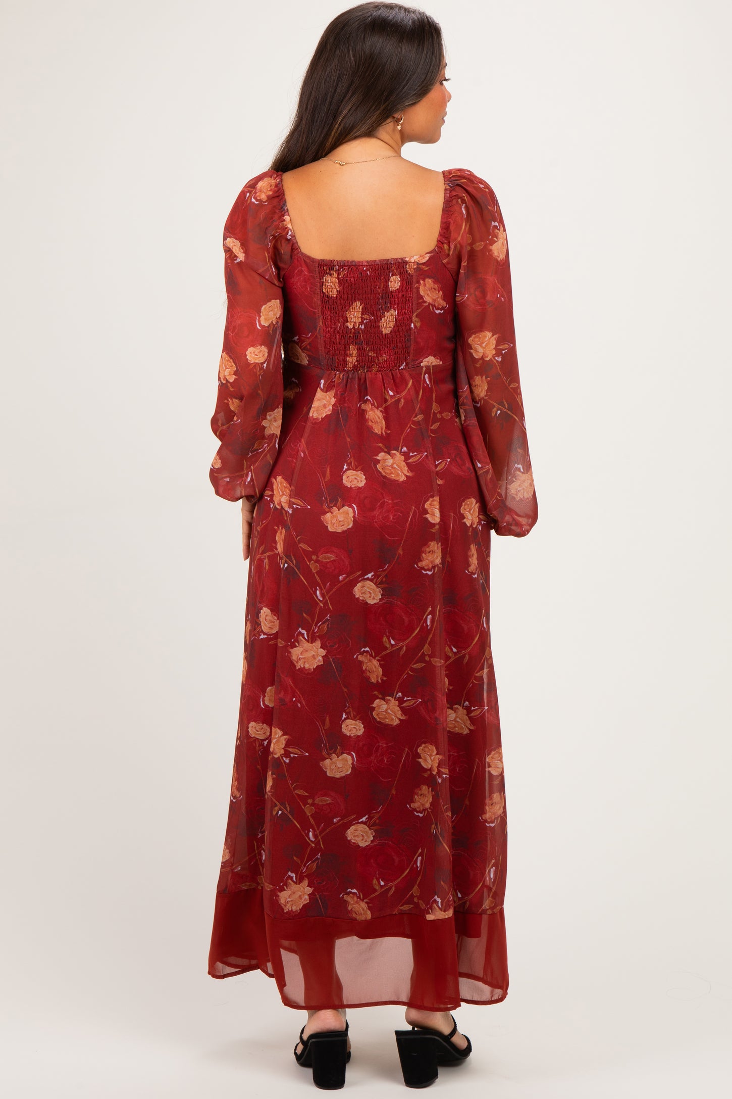 woman wearing a burgundy floral maternity maxi dress with long sleeves and a smocked back design