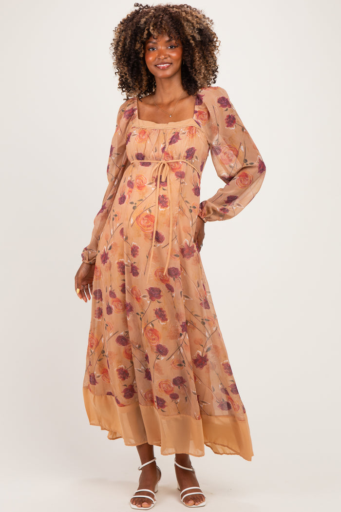 woman wearing a floral print maternity maxi dress with long sleeves and a tie waist, showcasing her baby bump