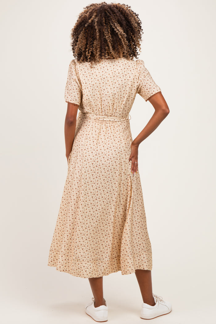 woman wearing a beige floral maternity dress with short sleeves and a waist tie, showing her back