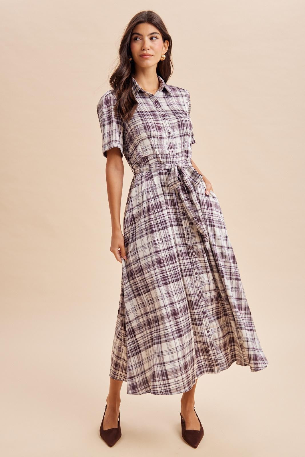 woman wearing a purple and white plaid button-up maxi dress with short sleeves and a tied waist