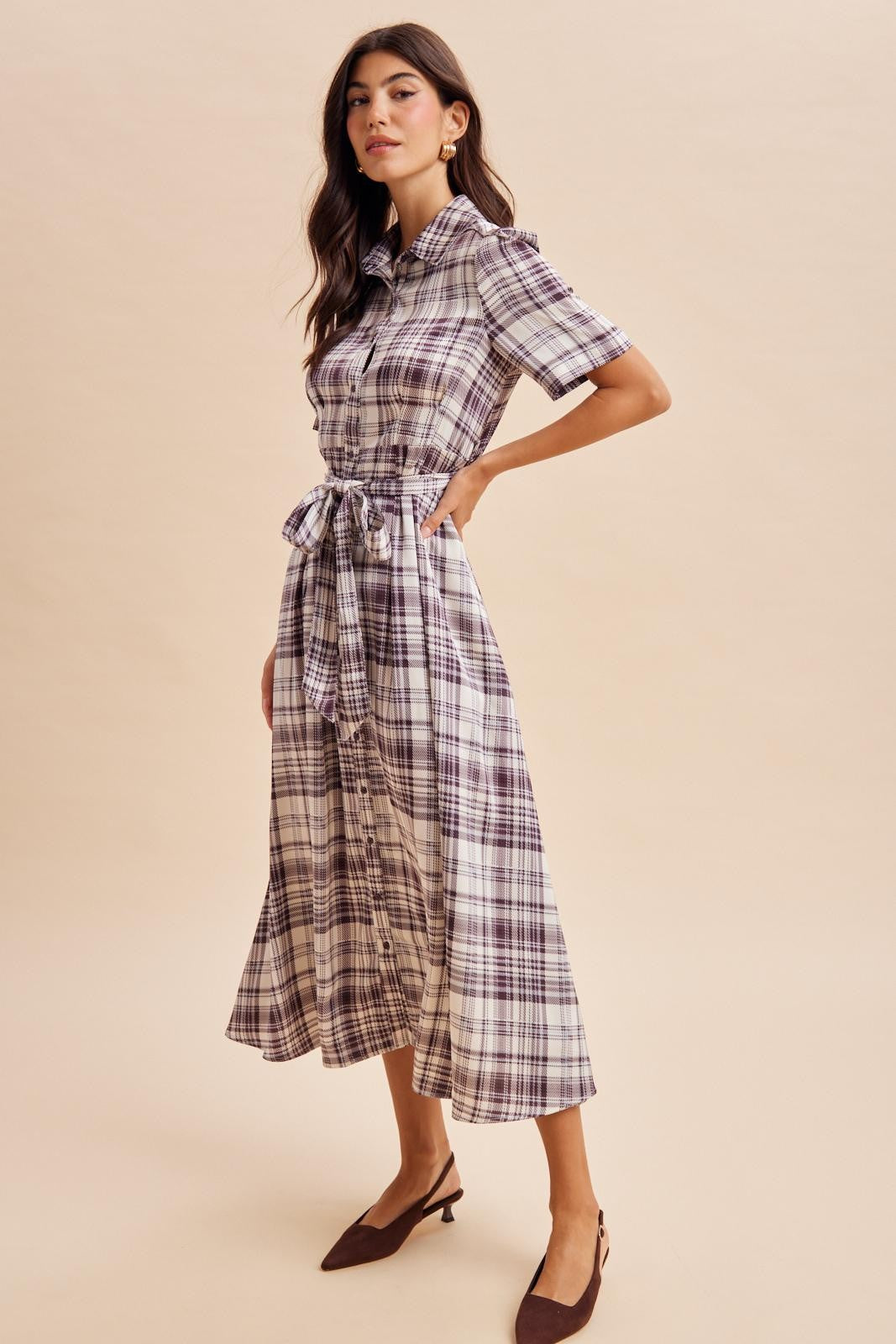 woman wearing a short sleeve plaid midi dress with a tie waist and brown heeled mules