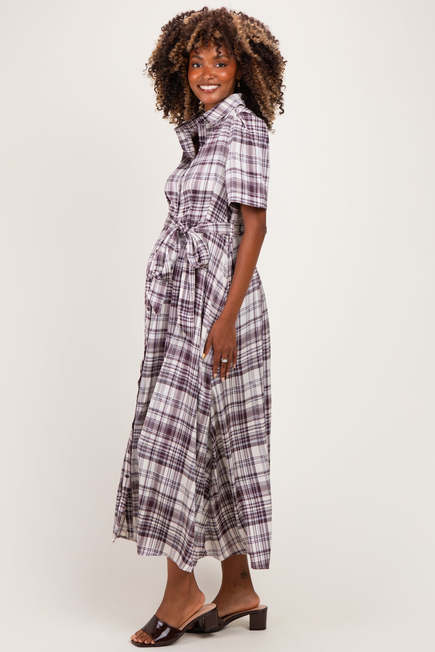 woman wearing a purple plaid maternity dress with short sleeves and a tie waist detail