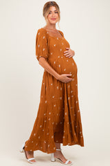 woman wearing a rust floral print maternity maxi dress and holding her baby bump