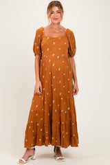 woman wearing a rust colored maternity maxi dress with puff sleeves and floral embroidery