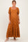 woman wearing a rust colored maternity maxi dress with puff sleeves and floral embroidery
