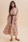 woman wearing a long sleeve beige maxi dress with floral embroidery and a tied waist belt