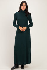 woman wearing a green turtleneck maternity dress that falls to the floor, styled with long sleeves and a relaxed fit