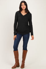 woman wearing a black long sleeve v-neck top with side ruching and blue skinny jeans, paired with brown knee-high boots