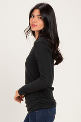 woman wearing a black long sleeve top with gathered side details and paired with blue jeans