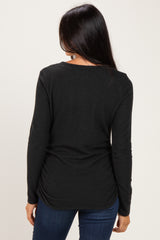 woman wearing a black long sleeve top with a scoop neck and gathered back detail, paired with blue jeans