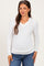 woman wearing a white long sleeve maternity top with a v-neck and showing her baby bump