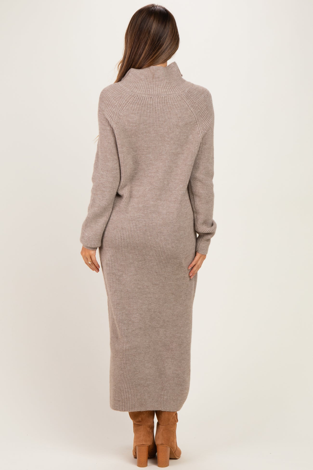 woman wearing a cozy beige maternity sweater dress with a high collar and long sleeves, showing a baby bump from the back