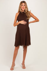 woman wearing a chocolate brown maternity dress with a halter neckline and holding her baby bump