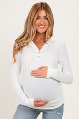 woman wearing a white maternity long sleeve hoodie with button details and holding her baby bump