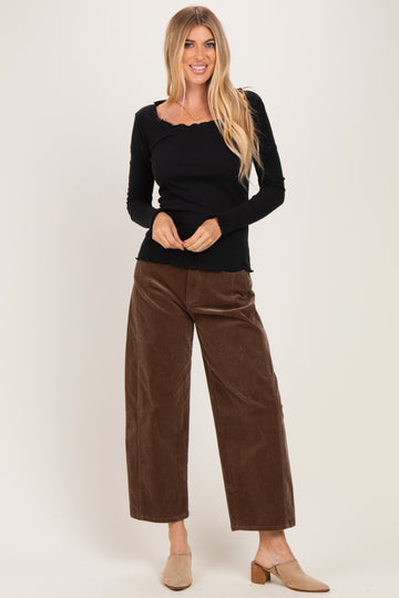 woman wearing a black long sleeve ribbed top with a scalloped neckline and brown wide-leg corduroy pants