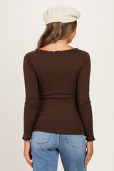 woman wearing a brown long sleeve maternity top seen from the back with distressed details and blue jeans