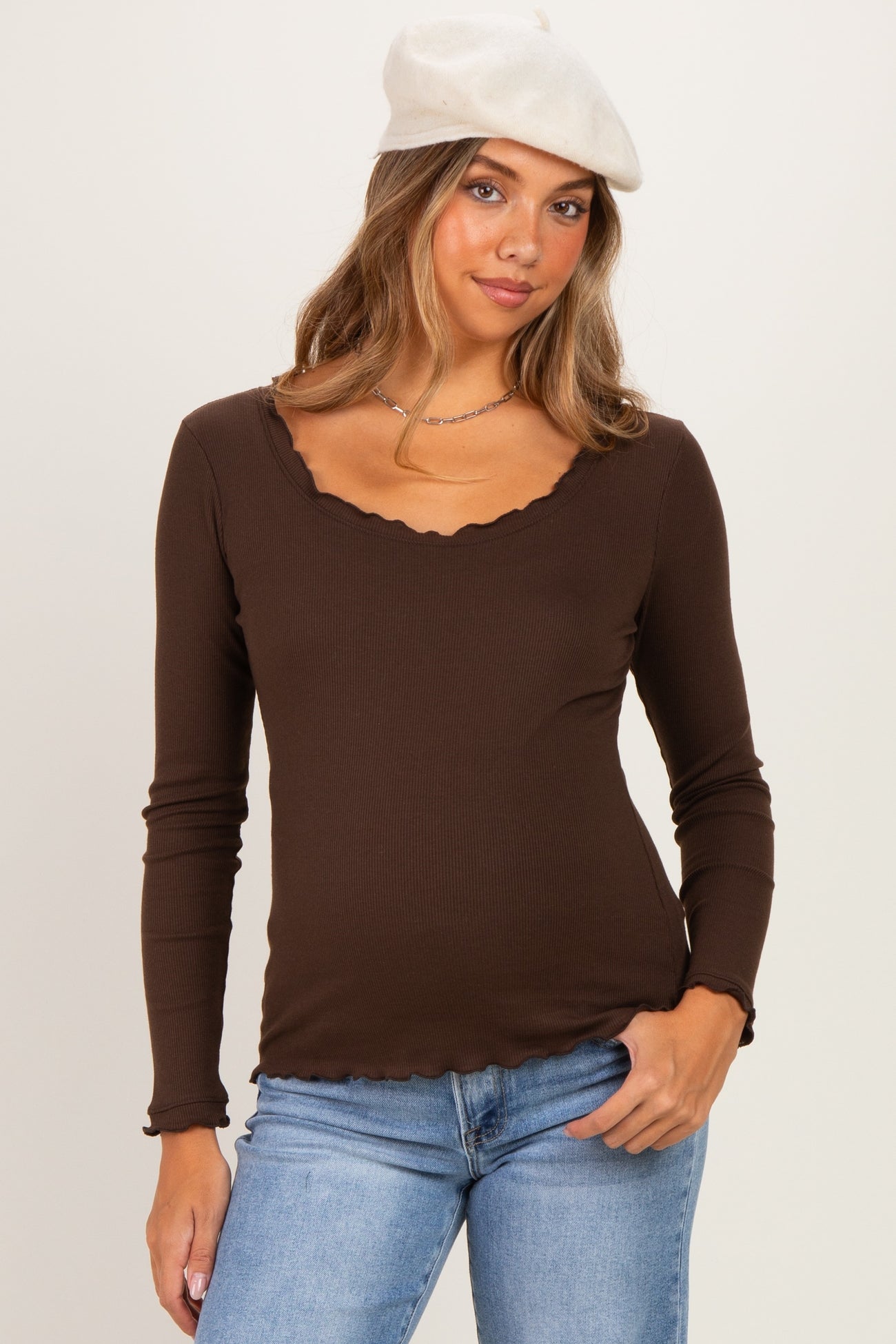 woman wearing a brown ribbed maternity top with a scalloped neckline and long sleeves
