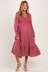 woman wearing a dusty rose maternity dress with a smocked bodice and tiered skirt, showcasing her baby bump