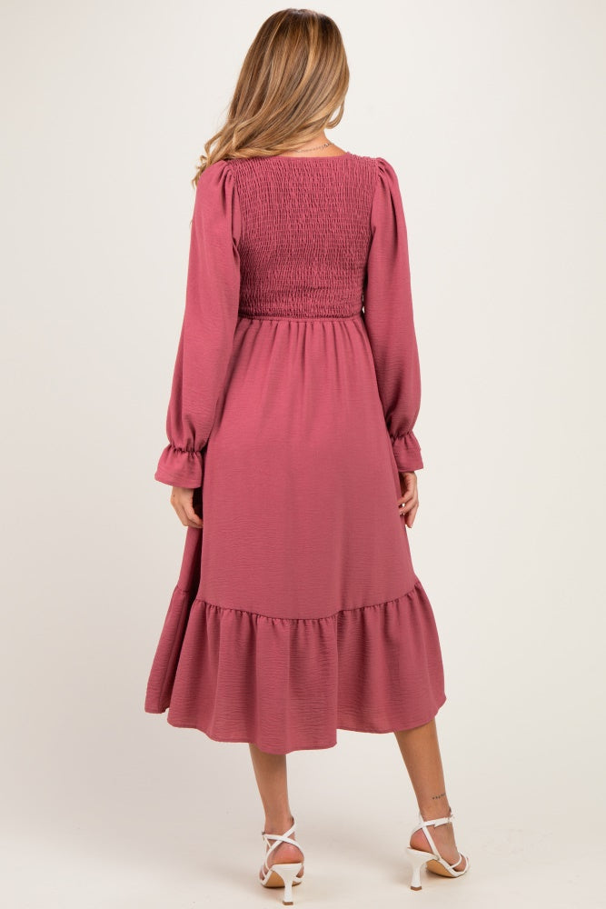 woman wearing a dusty rose long sleeve maternity dress with a smocked bodice and a ruffled hem
