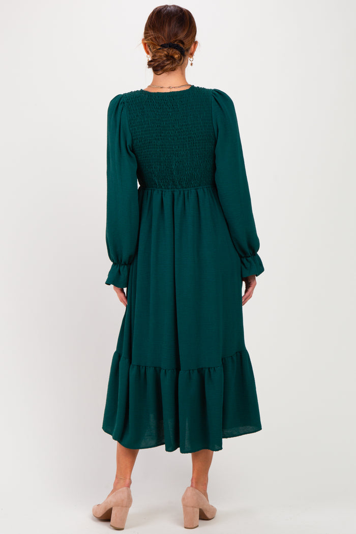 woman wearing a green long sleeve midi dress with smocked back and tiered skirt, seen from the back