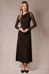woman wearing a fitted brown long sleeve dress with a draped bodice and sheer sleeves